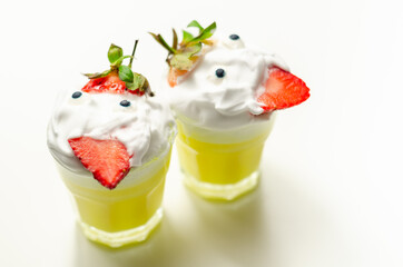 Egg liqueur in shot glass decorated with fluffy whipped cream and pieces of strawberry, served in funny way