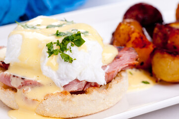 Closeup shot of eggs benedict with farm fresh eggs and ham and fried potatoes