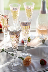 A vertical view of several tall crystal flute glasses filled with sparkling rose wine, back lit against a sunny window.