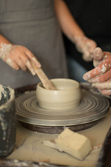 human hands make a clay product on a potter's wheel