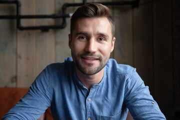 Head shot happy millennial generation male blogger recording video or streaming online educational course. Smiling motivated male applicant passing distant job interview, communicating remotely.
