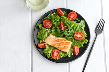 Delicious fresh salad with fish, tomatoes and lettuce leaves