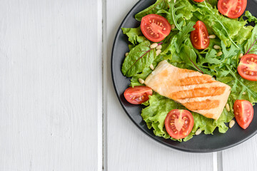 Delicious fresh salad with fish, tomatoes and lettuce leaves