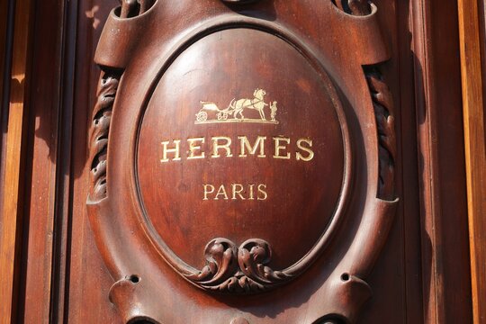 Enseigne et logo de la c&eacute;l&egrave;bre marque de mode de luxe fran&ccedil;aise Herm&egrave;s sur la devanture en bois sculpt&eacute; d&rsquo;une boutique &agrave; Paris &ndash; mai 2021 (France)