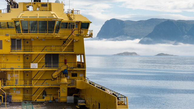 A yellow supply ship at sea heading into deep fog.