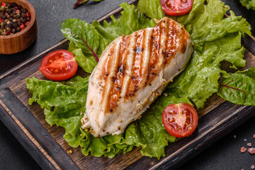 Pieces of chicken, tomatoes and lettuce leaves on a dark concrete background