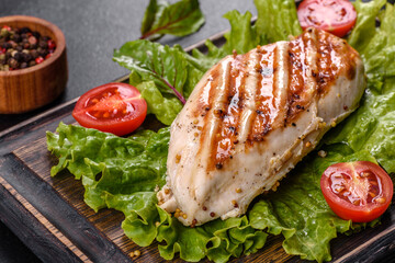 Pieces of chicken, tomatoes and lettuce leaves on a dark concrete background