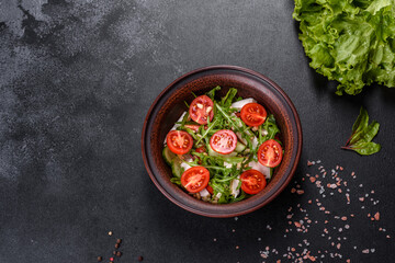Pieces of chicken, tomatoes and lettuce leaves on a dark concrete background