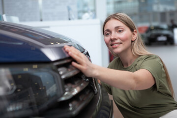 Fototapeta na wymiar Beautiful woman examining new car at auto dealership, looking for auto to buy