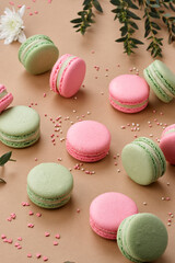 Macarons surprisingly tender green and pink colors neatly laid out on a beige background. View from above.