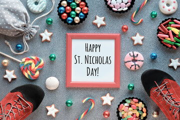Text Happy St Nicolas Day in red frame. Traditional holiday in Germany and Western Europe on December 6. Various sweets, candy, cookies and pair of shoes on silver festive background.