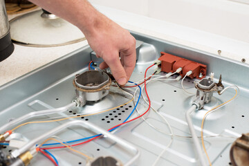 man hand repairs hotplate of gas panel with screwdriver
