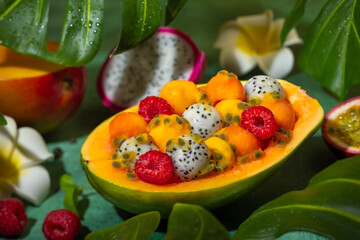 Summer exotic fruit salad in half of papaya. Healthy sweet dessert with mango, papaya, pitaya, passion fruit and raspberry.