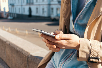 Close-up young woman wearing beige coat typing