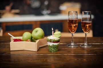 Champagne in glasses and a bowl of fruit on a wooden table top in a cafe.