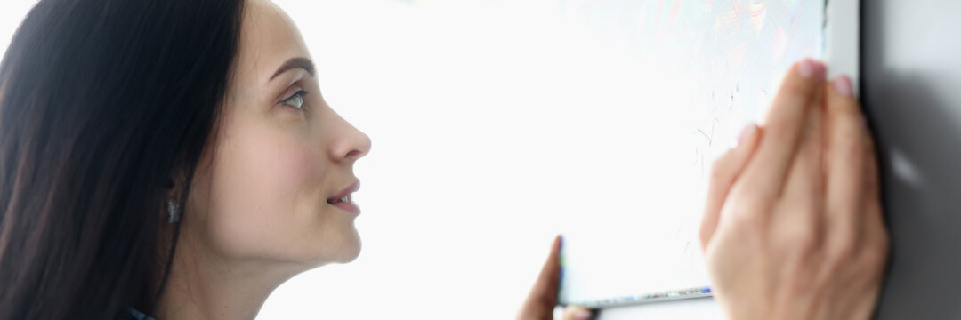 Woman hanging picture on wall at home