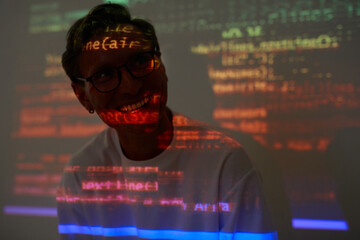 Computer hacker sitting in dark room and smiling he working with computer program