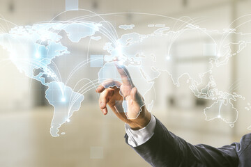 Man hand clicks on abstract graphic digital world map with connections on blurred office...