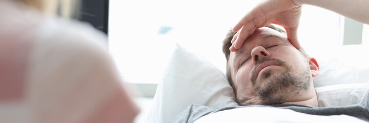 Naklejka premium Woman visitor holding hand of sick man in hospital room
