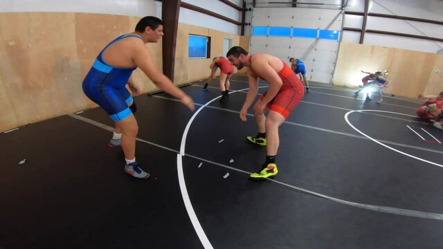 Pair of heavy weight wrestlers going live during a coed group wrestling practice.