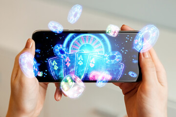 Creative background, online casino, in a man's hand a smartphone with playing cards, roulette and...