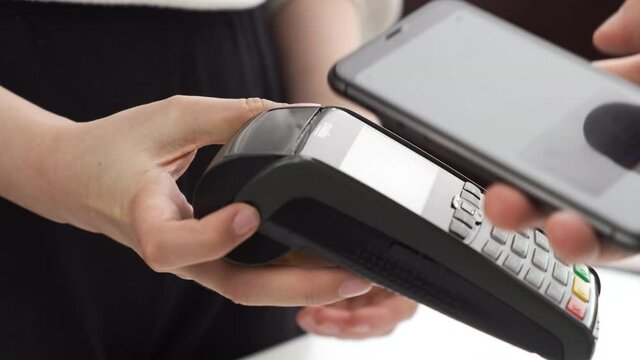 Close up womans hand pushing the buttons or sum of purchase on pos terminal. A seller enters the amount on the terminal