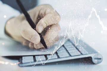 Multi exposure of abstract financial diagram with world map and with hand writing in notepad on background with laptop, banking and accounting concept