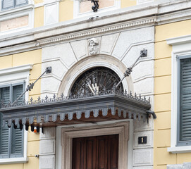 entrance sheltered by an ancient canopy surmounted by an arched fanlight in artistic wrought iron and a band with geometric motifs
