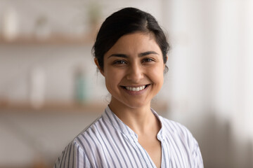 Headshot close up portrait of smiling young Indian woman look at camera feel positive optimistic. Profile picture of happy millennial mixed race female renter or tenant. Diversity concept.