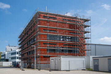 construction site of a building with scaffolding at the outside, blue sky 