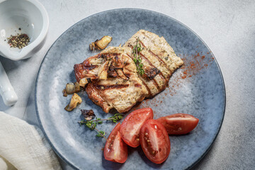 Pork steaks with tomatoes on a plate close-up view from above