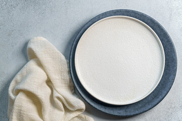 White plate with napkin on light concrete background. Top view, with copy space - 440647673