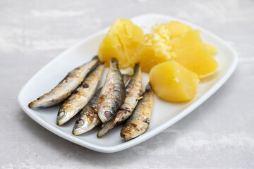 fried sardines with boiled potato on white dish