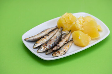 fried sardines with boiled potato on white dish