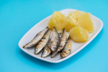 fried sardines with boiled potato on white dish