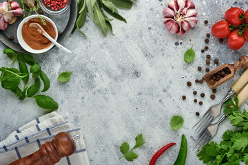 Food cooking background. Fresh saffron, garlic, cilantro, basil, cherry tomatoes, peppers and olive oil, spices herbs and vegetables at light grey slate table. Food ingredients top view.