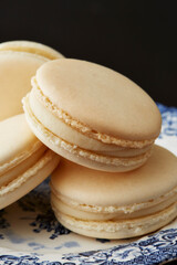 A close up stack of french macarons on a vintage blue and white plate