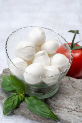 Fresh white soft mini mozzarella balls served with red tomato and fresh green basil