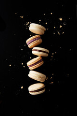 Assorted french macarons and crumbs on a black surface