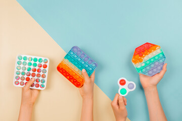 Many hands holding trendy pop it fidget toys on colorful background. Push pop-it fidgeting game...