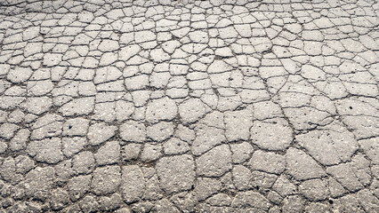 The texture of cracked old asphalt in need of repair. The road is full of holes and potholes. Pit repair