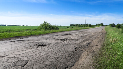The texture of cracked old asphalt in need of repair. The road is full of holes and potholes. Pit repair