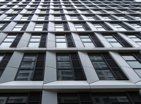 Close Up Perspective Detail Of Tall High Rise Modern Apartment Building With Geometric White Cladding And Dark Windows