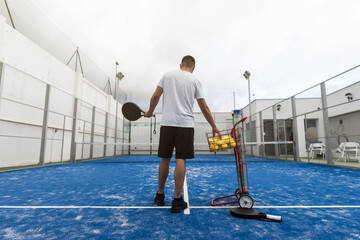Fototapeta na wymiar young boy catches balls to train with paddle tennis on a cloudy day