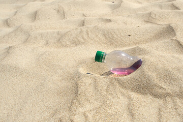 Fototapeta na wymiar Plastic bottle with a drink in the sand.
