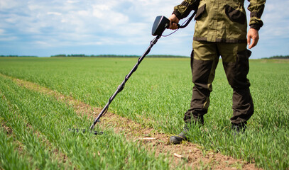 metal search with a metal detector in the field. hand without face
