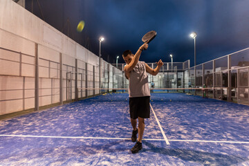 Fototapeta na wymiar paddle tennis training, young man bounces balls against glass