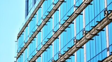 Abstract closeup of the glass-clad facade of a modern building covered in reflective plate glass. Architecture abstract background. Glass wall and facade detail.