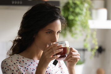 Head shot close up of beautiful woman drinking black tea, enjoying morning, breakfast, starting new...