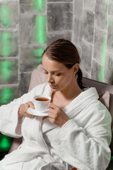 Inhalation therapy in salt room in spa. Young woman with cup of tea relaxing.